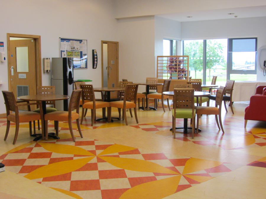 Our Skye Centre Atrium - a cafe like space with tables and chairs, with views of outdoor green space.